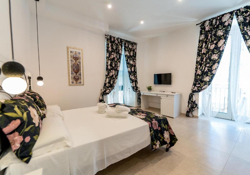 a bedroom with a bed and a tv and windows at SAN BARTOLOMEO BAROQUE in Scicli