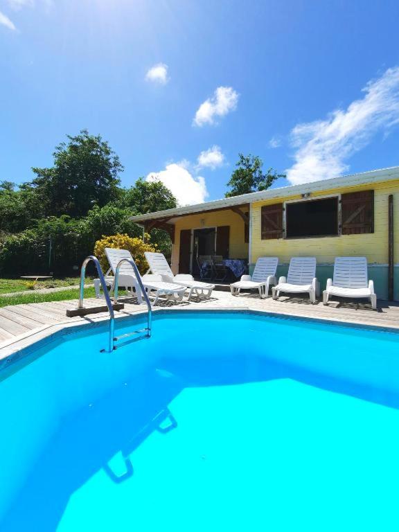 a swimming pool with chairs and a house at Villa de 2 chambres avec piscine privee jardin clos et wifi a Le Marin a 1 km de la plage in Le Marin