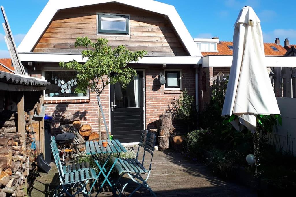 a house with an umbrella and a table and a bench at Olga's Cottage in Den Helder