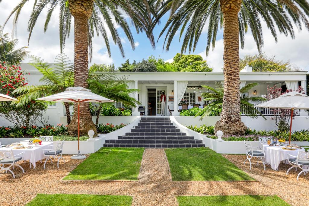 widok na przednią część ośrodka ze stołami i palmami w obiekcie Villa Coloniale Schumacher Luxury Retreat w Kapsztadzie