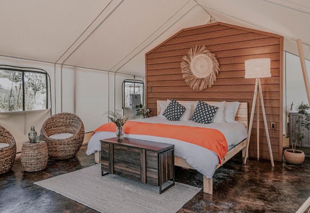a bedroom with a large bed with a wooden headboard at Salterra Glamping in Tequisquiapan