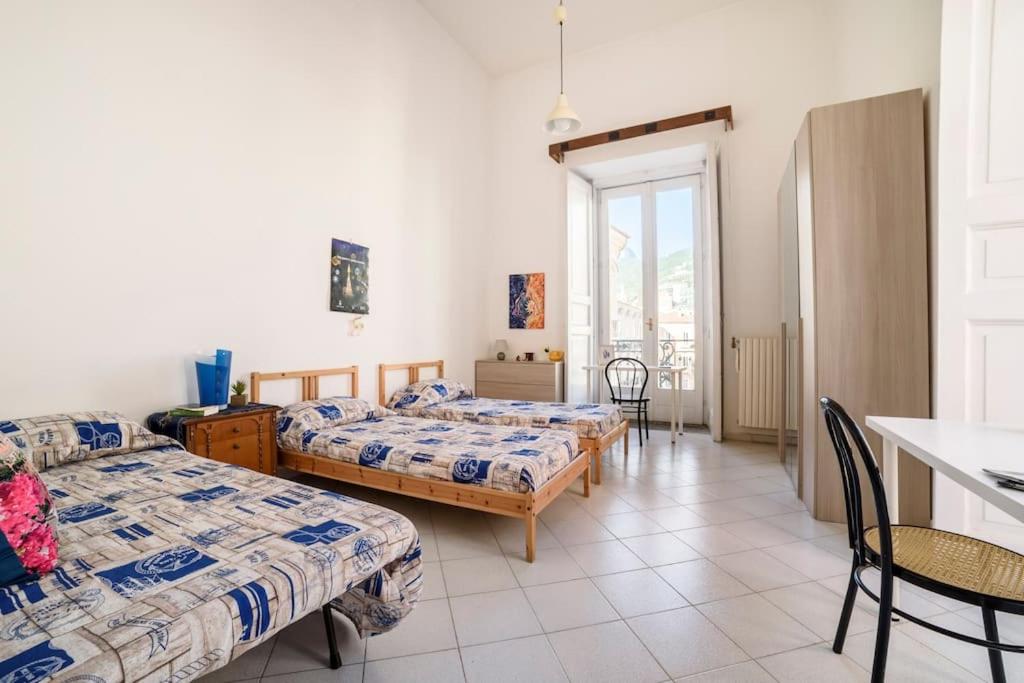 a room with three beds and a table and chairs at Il Soffione Centro Storico in Salerno
