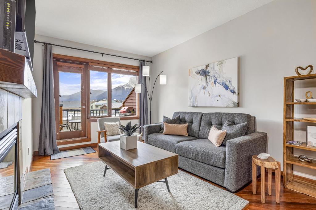 a living room with a couch and a table at Alluring Mountain View Condo -Right In The Heart Of Downtown!! Hosted by Fenwick Vacation Rentals in Canmore