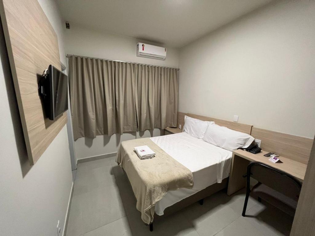 a hotel room with a bed and a television at Santa Rosa Hotel in Assis