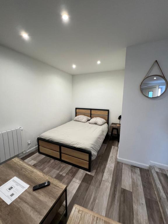 1 dormitorio con cama, mesa y espejo en Superbe appartement avec parking gratuit sur place, en Blanzy