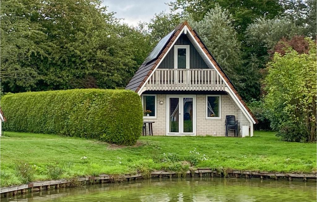 a small house on a lawn next to a pond at Pet Friendly Home In Gramsbergen in Gramsbergen