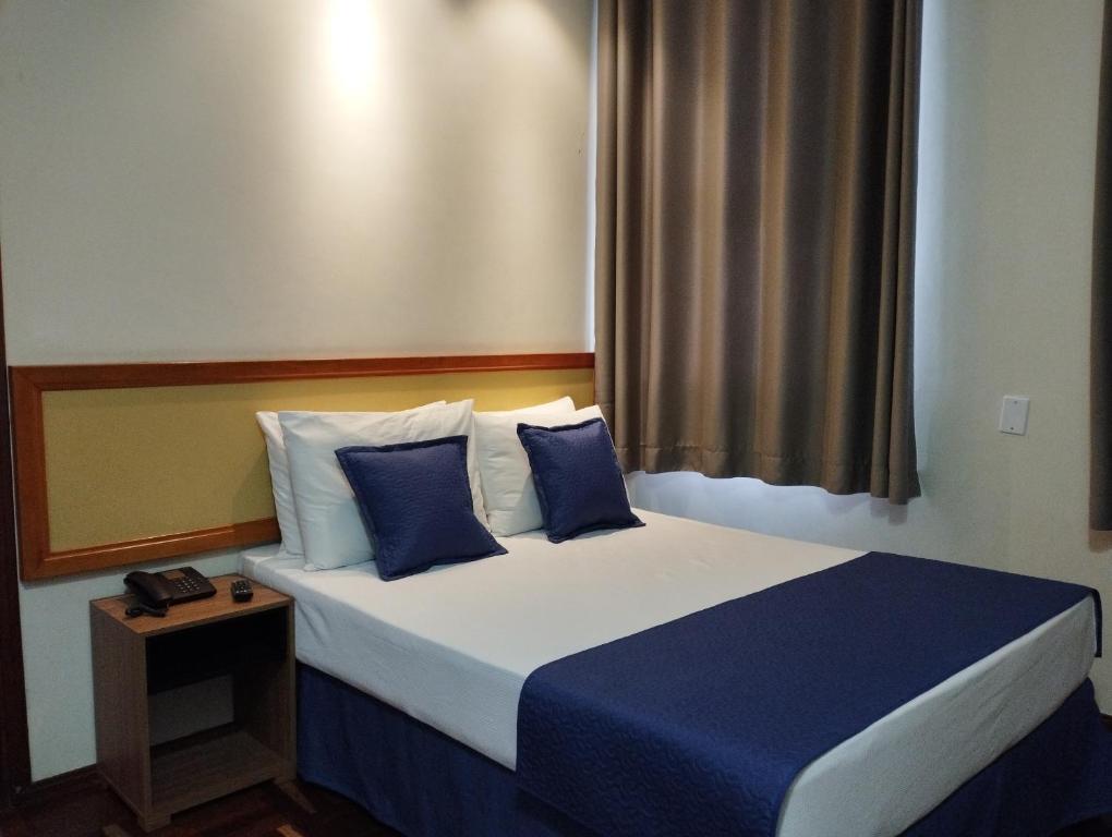 una camera da letto con un letto con cuscini blu e bianchi di Summit Inn Hotel Pouso Alegre a Pouso Alegre