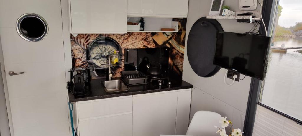 een kleine keuken met een wastafel en een klok aan de muur bij Hausboot Lucky in Hattem