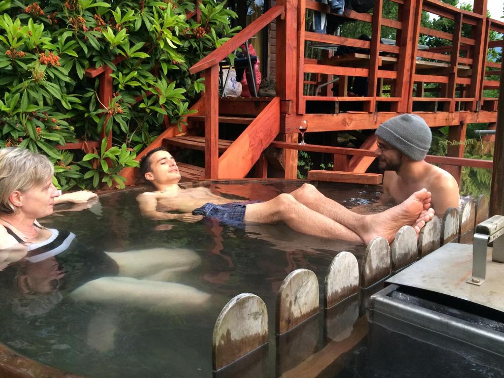 un grupo de personas sentadas en una bañera de hidromasaje en Loft Canelo - con hot tub exclusivo, cercano a termas y lago, en Coñaripe