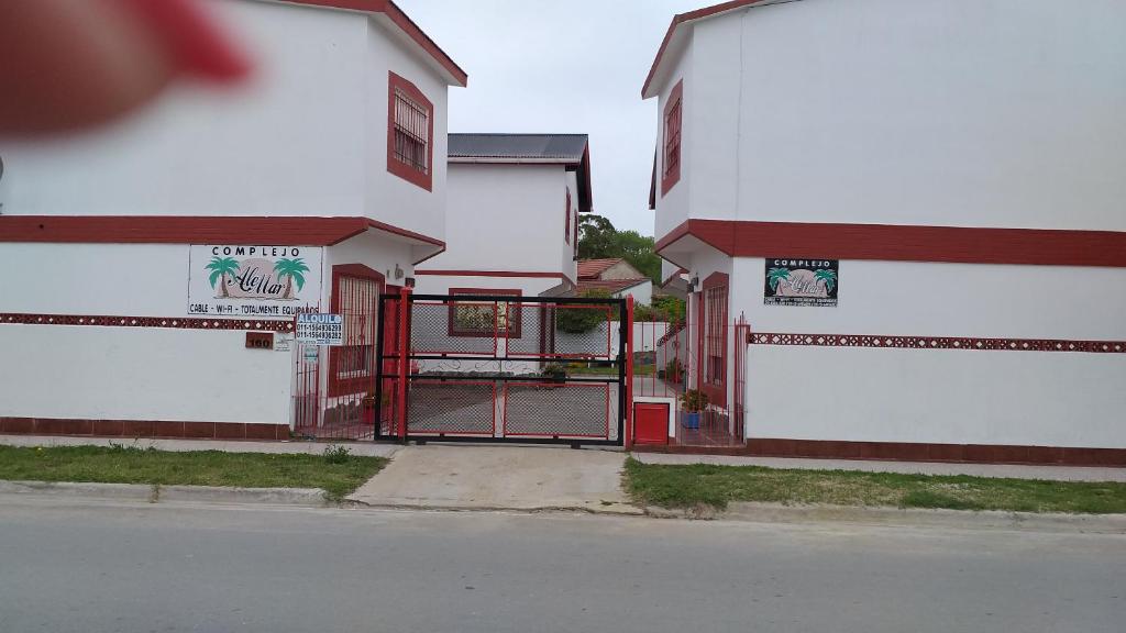 un edificio blanco con una puerta roja al lado de una calle en Complejo AleMar en San Clemente del Tuyú