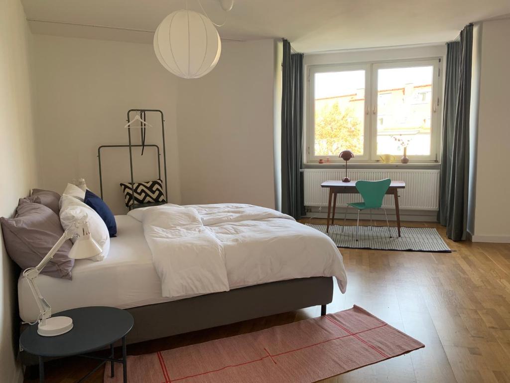 1 dormitorio con cama, mesa y ventana en Charmante Stadtwohnung im Textilviertel, en Augsburg