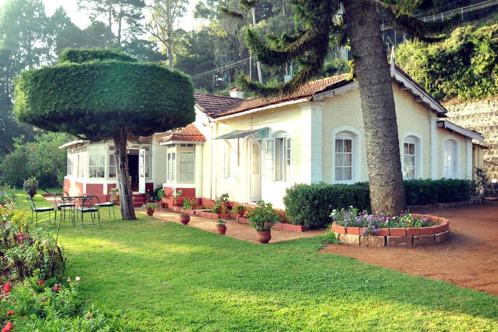 a house with a tree and flowers in a yard at Wyoming Heritage in Ooty