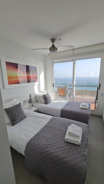 two beds in a bedroom with a view of the ocean at MIRADOR in Denia