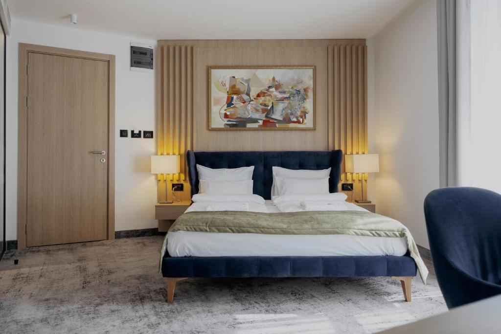 a bedroom with a large bed with a blue headboard at WellNS Rooms in Novi Sad