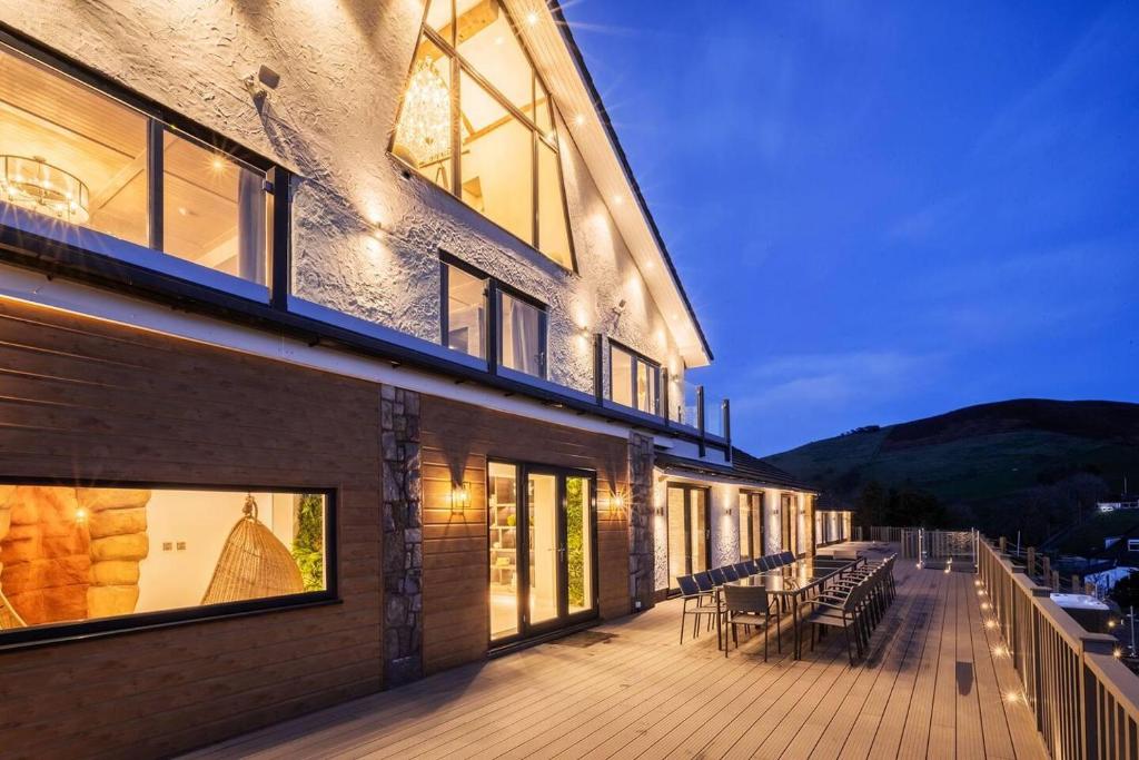 a building with a deck with tables and chairs at Clwyd Gate Manor Pool Sauna HotTub Cave Wales in Ruthin