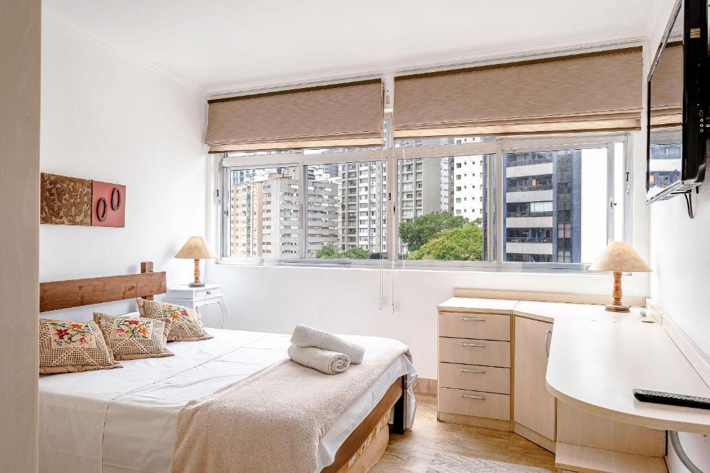 a bedroom with a bed and a desk and a sink at Apê com janelão | 300 m da Av. Paulista in São Paulo