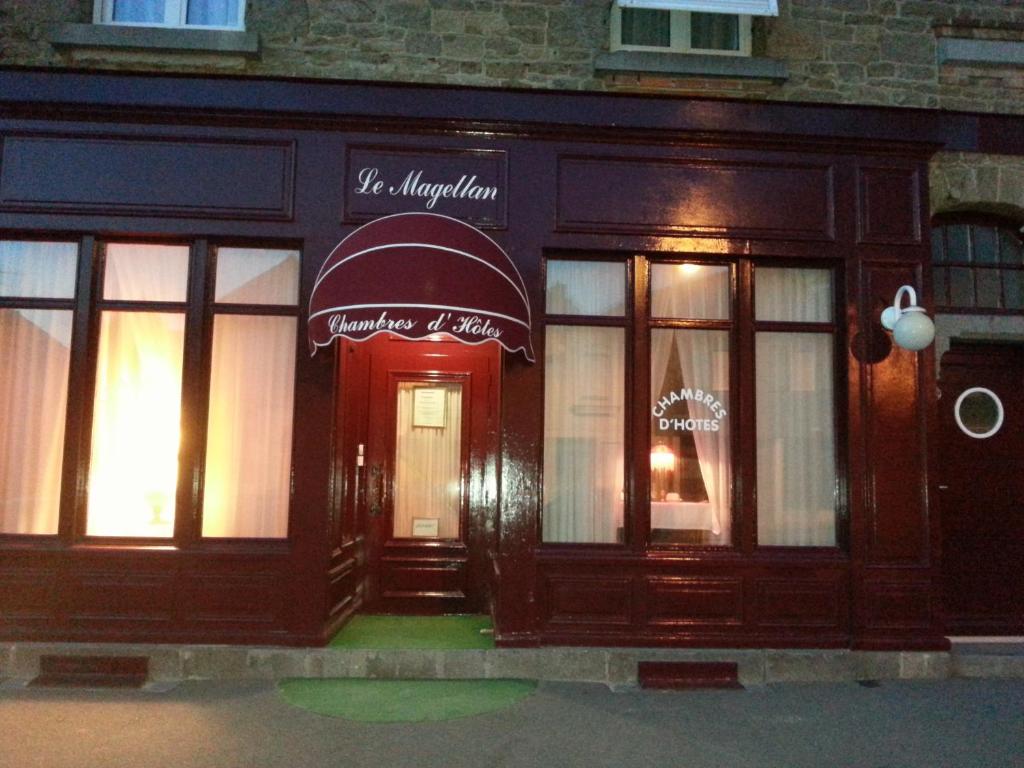 une façade de magasin avec une porte rouge et des fenêtres dans l'établissement Le Magellan-Plage, à Saint-Malo