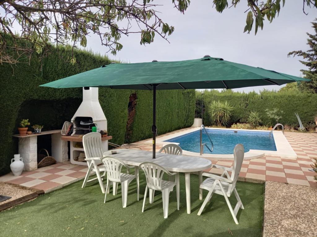 a table and chairs under an umbrella next to a swimming pool at Casa Rural Xauen in Belicena