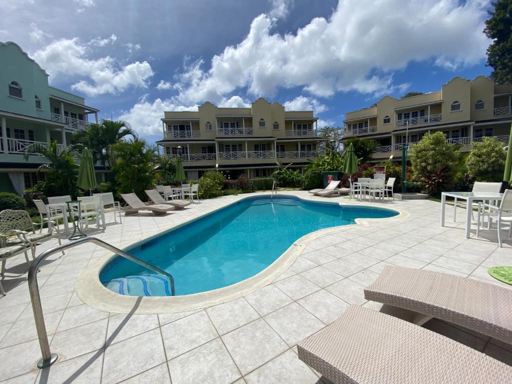 a pool at a resort with chairs and tables at 25 Margate Gardens in Bridgetown