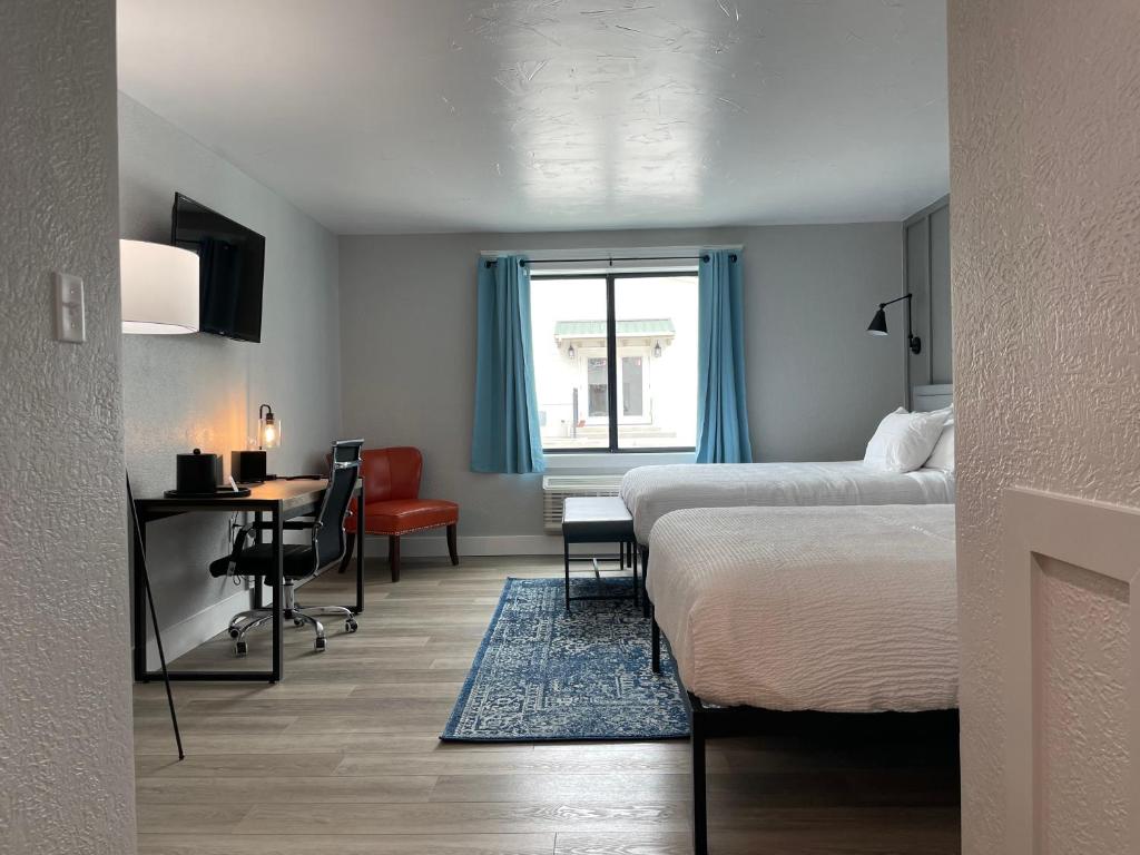 a hotel room with two beds and a desk and a table at The Hermitage Inn and Taphouse in Petersburg