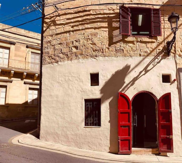 a building with red doors on the side of it at 300yr old, self catering, tiny house in Victoria Centre, Gozo in Victoria