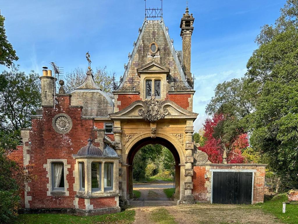 um antigo edifício de tijolos com uma entrada em arco em Historic 2 bed gatehouse in private parkland em Brockenhurst
