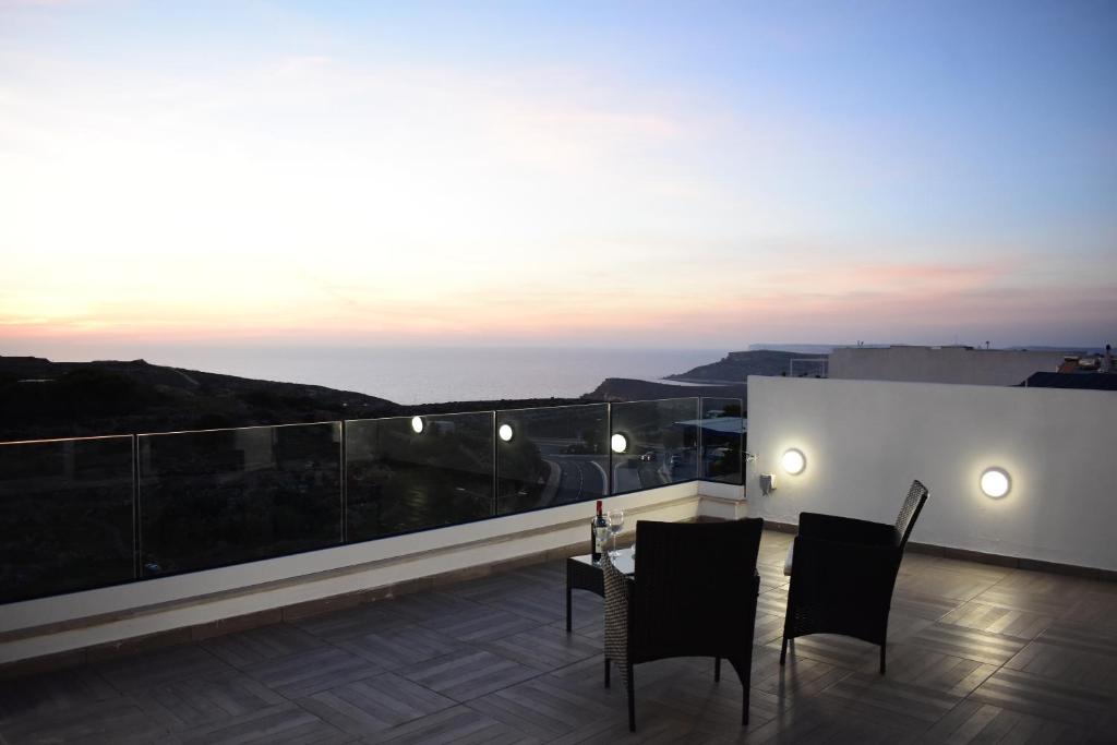 a patio with a table and chairs on a balcony at Sunset and Seaview Apartment -Brand New in Mellieħa