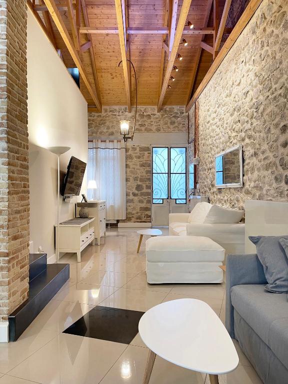 a living room with white furniture and a brick wall at Blue Domino Luxury City Villa Patras in Patra