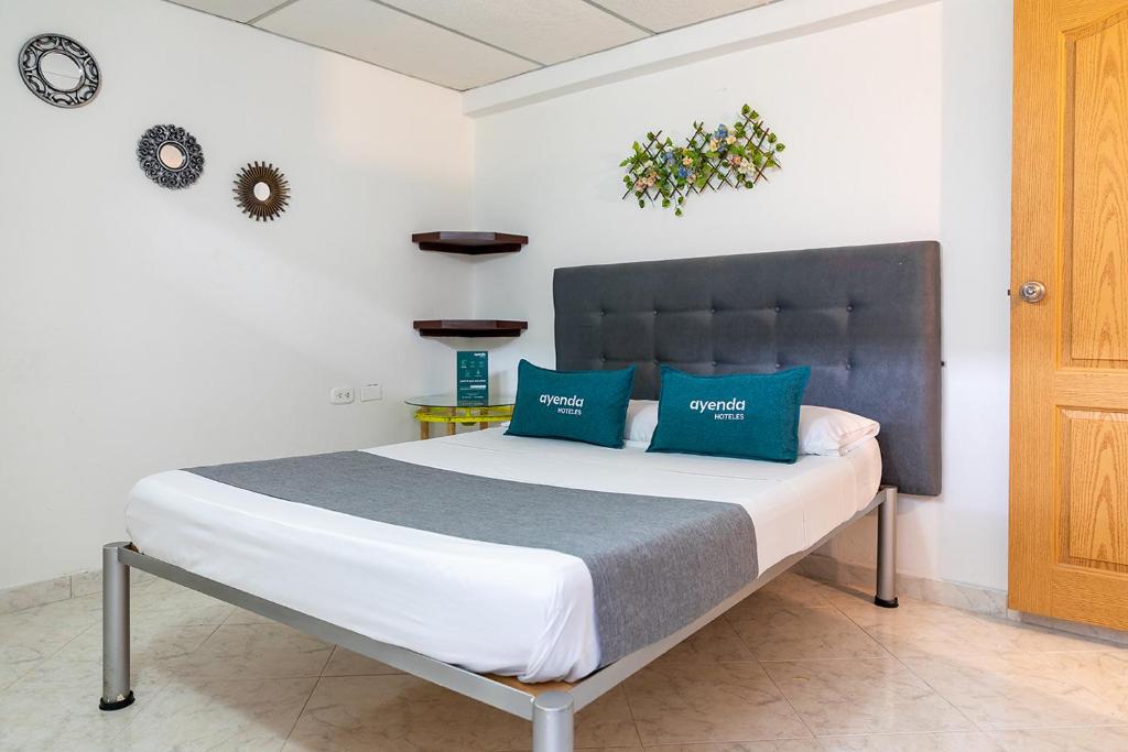 um quarto com uma cama grande e almofadas azuis em Hotel Ayenda Guadalupe em Neiva
