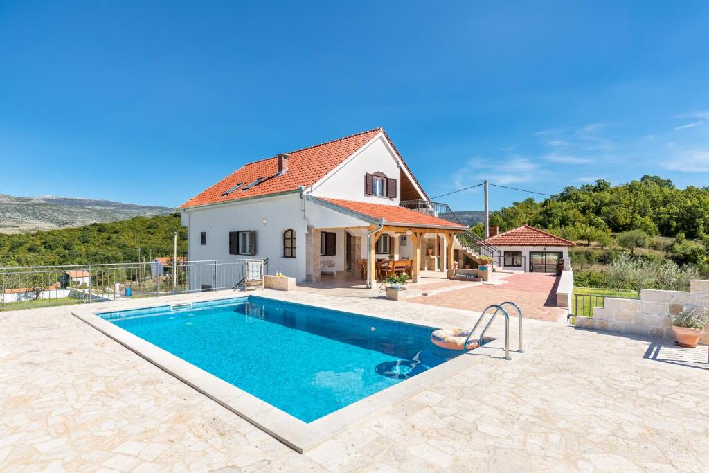 eine Villa mit einem Swimmingpool vor einem Haus in der Unterkunft Villa Sinodium in Umljanović