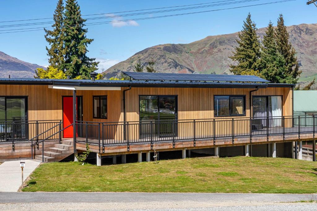 ein Haus mit einer Terrasse und Bergen im Hintergrund in der Unterkunft Elevated Mountain Views in Wanaka