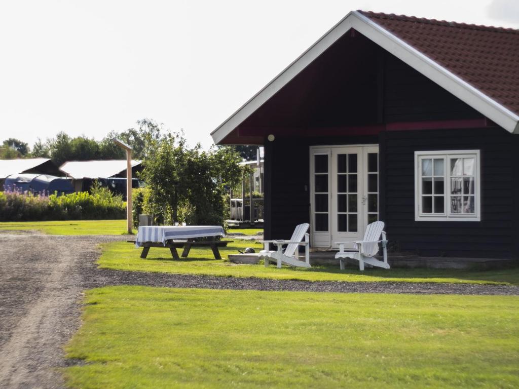 a black house with a picnic table and a bench at Chalet in Friesland near Alde Feanen in De Veenhoop