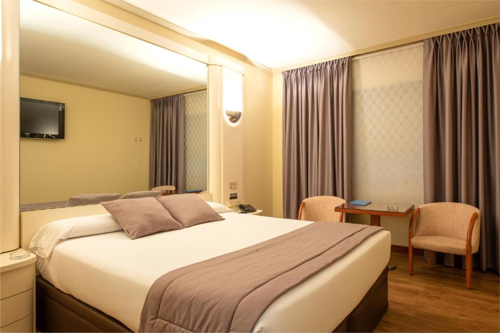 um quarto de hotel com uma cama grande e uma secretária em Motel Jardin em Oleiros