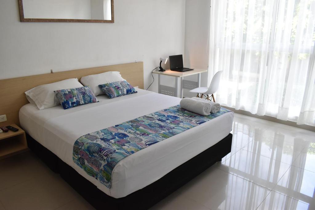 a bedroom with a bed and a desk and a window at Color House Santa Marta in Santa Marta