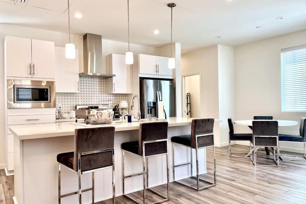 a kitchen with white cabinets and a kitchen island with chairs at Mills SACRAMENTO TOWNHOUSE NEAR DOWNTOWN in Sacramento