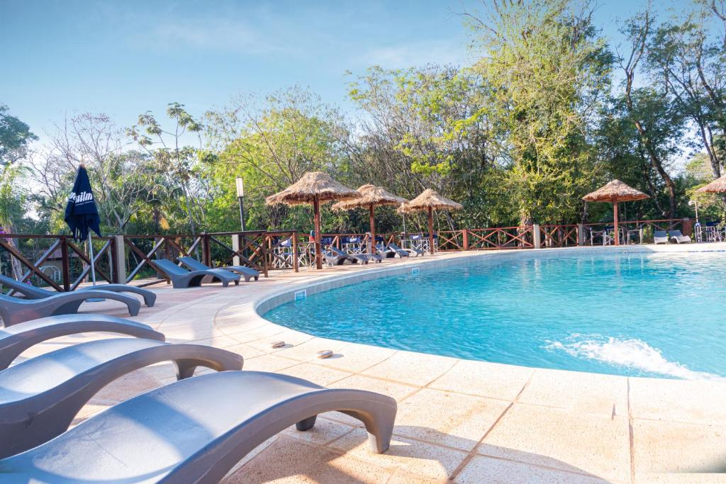 uma grande piscina com cadeiras e guarda-sóis em Village Cataratas em Porto Iguaçu