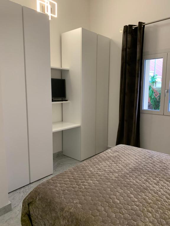 ein weißes Schlafzimmer mit einem Bett und einem TV in der Unterkunft Villetta Gramsci, Alassio in Alassio