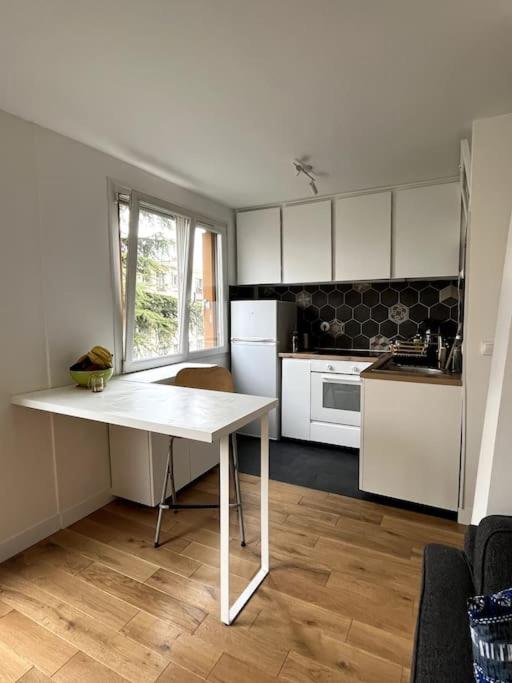 a kitchen with a white table in a room at Appartement de standing calme - Paris - Métro 9 in Montreuil