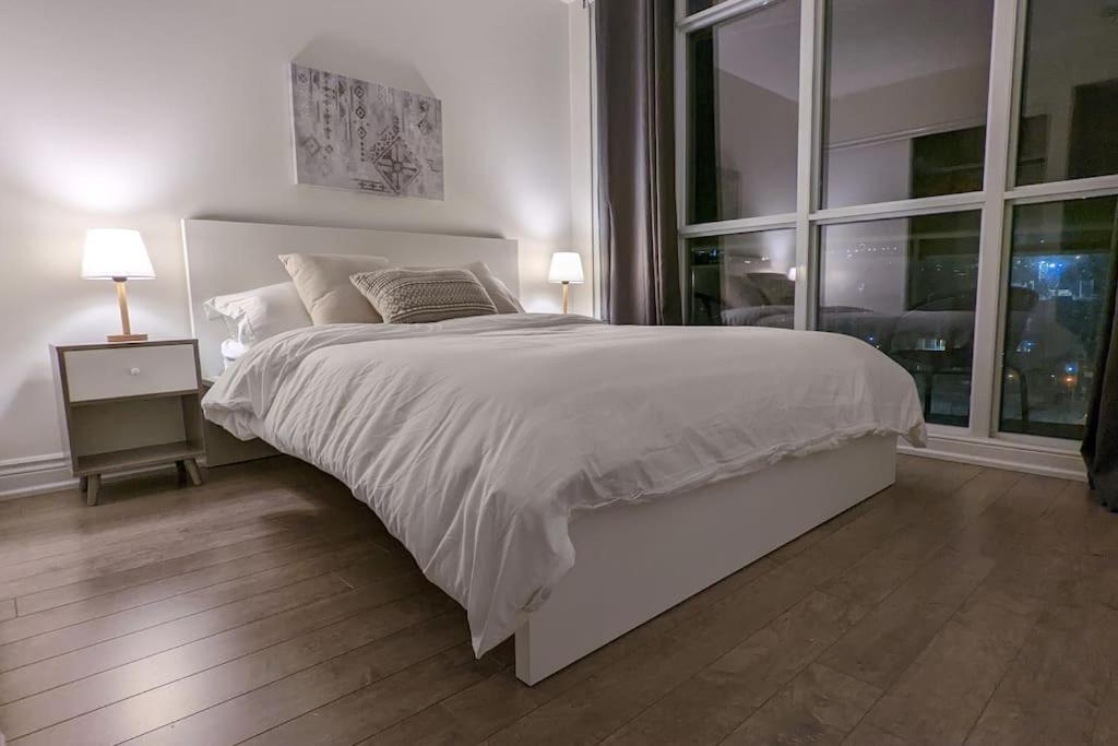 a white bedroom with a large bed and a window at Lovely 2 Bed Condo in Downtown Toronto in Toronto