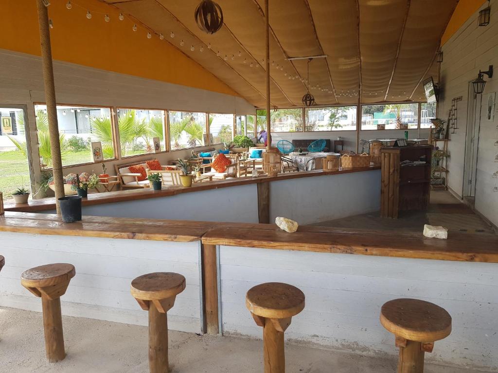a restaurant with wooden stools in front of a counter at Hotel Del Valle Quilimari in Pichidangui