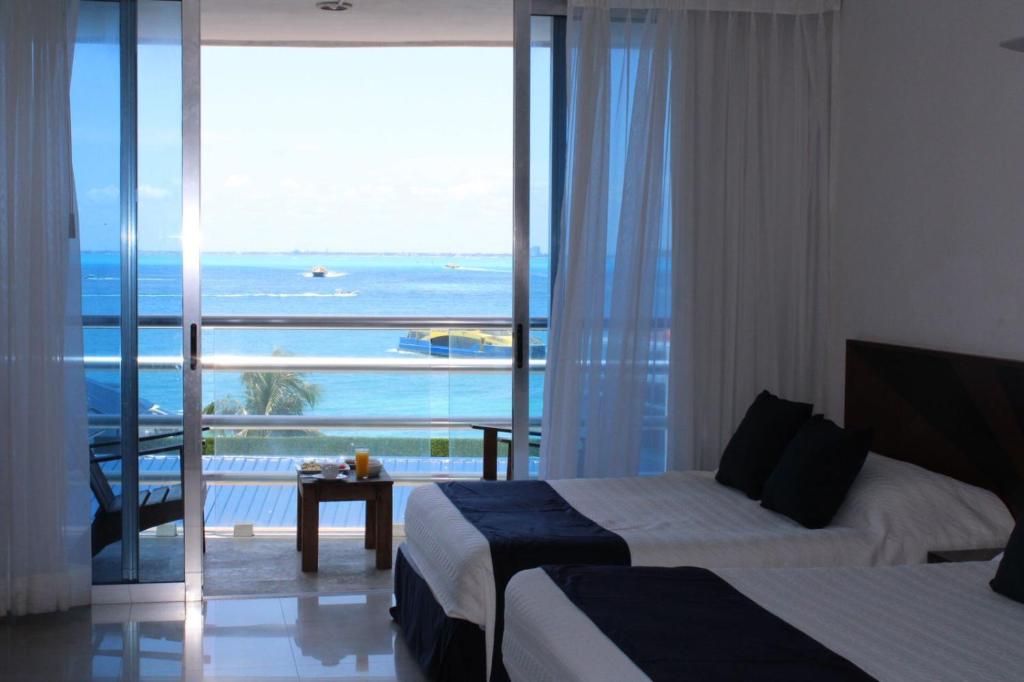 a hotel room with two beds and a view of the ocean at Bahia Chac Chi - Adults Only in Isla Mujeres