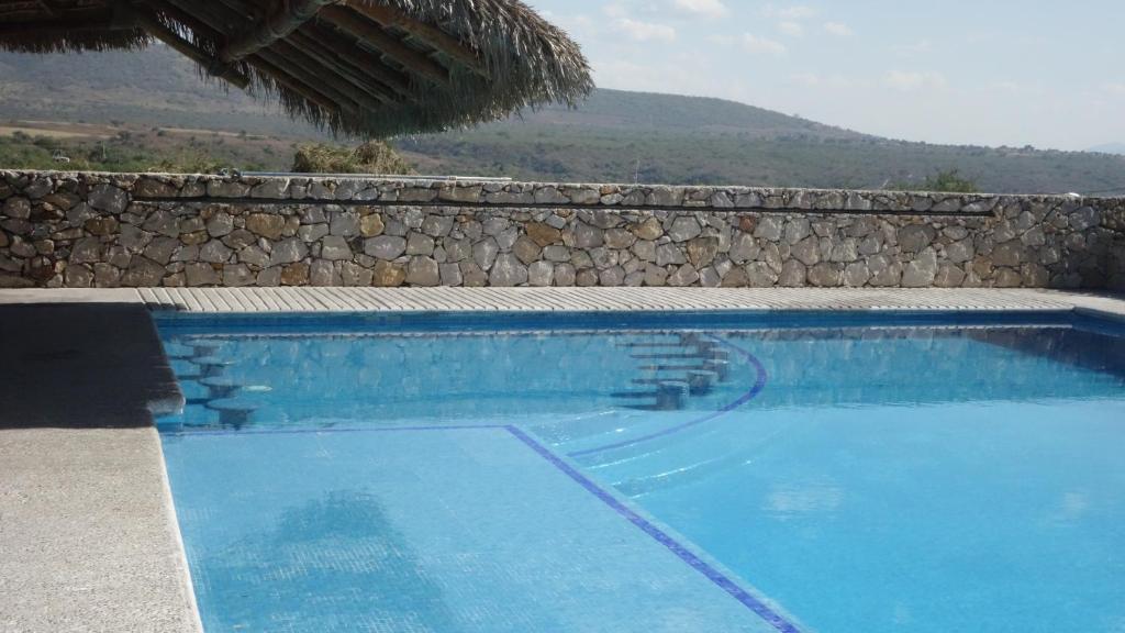 une piscine bleue avec un mur en pierre dans l'établissement Casa de Piedra. Tequesquitengo, à Tequesquitengo