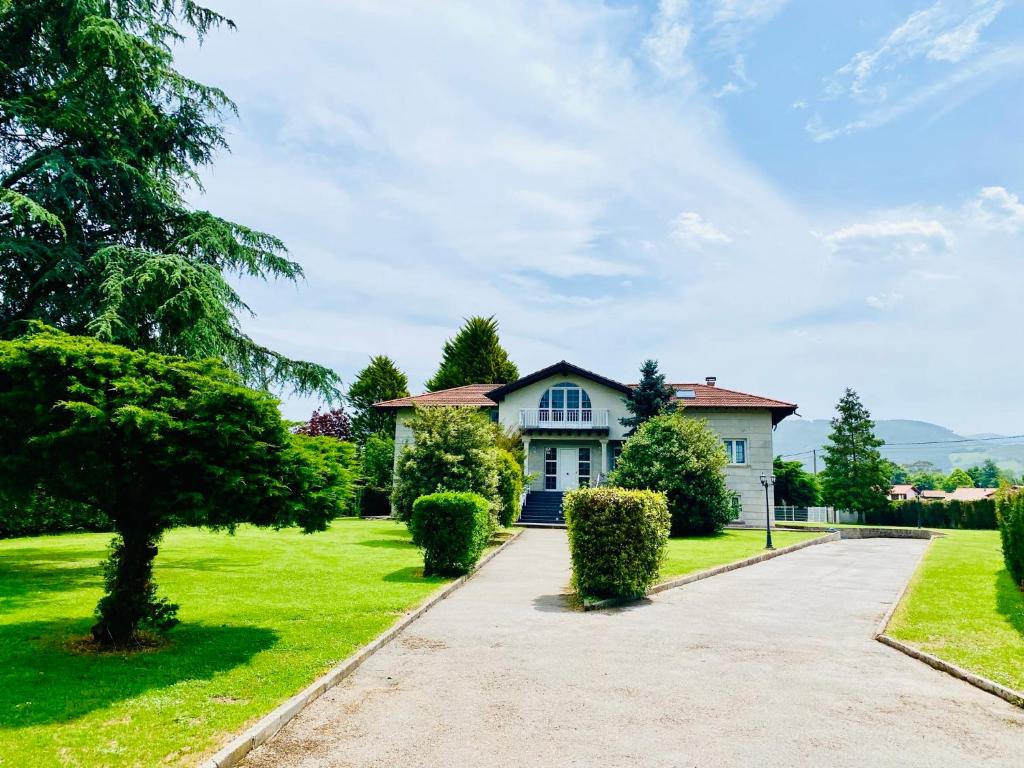 une grande maison blanche avec une allée. dans l'établissement María Bonita Chalet Villa independiente con piscina y amplio jardín, à Cabezón de la Sal