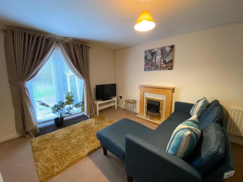 a living room with a blue couch and a fireplace at Wellingborough Cosy Hub in Harrowden