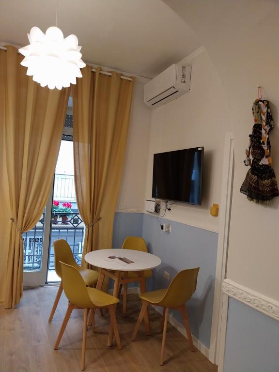 salon ze stołem, krzesłami i telewizorem w obiekcie Fra&Fra's home nel cuore del centro storico di Napoli w mieście Neapol