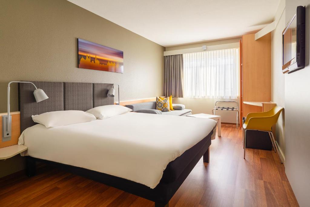 una habitación de hotel con una gran cama blanca. en ibis Hotel Würzburg City, en Würzburg