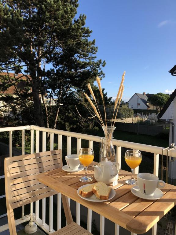 - une table en bois avec de la nourriture et des boissons sur une terrasse dans l'établissement Les Alisés, à Merville-Franceville-Plage