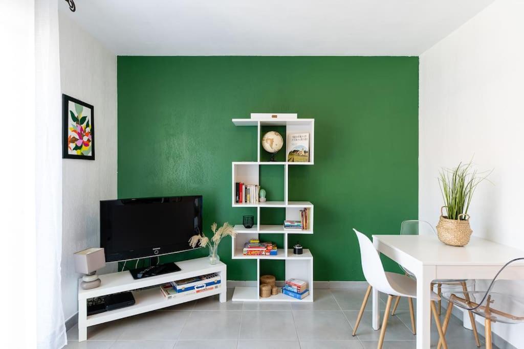 uma sala de estar com uma parede verde e uma televisão em Appartement cosy em Biscarrosse