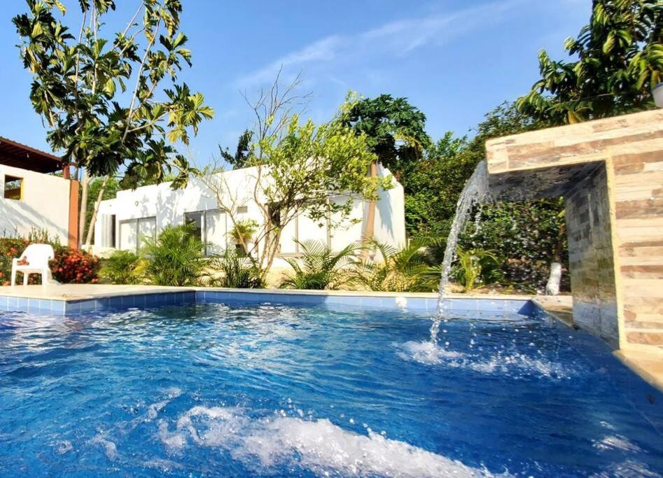 a swimming pool with a water fountain in a yard at Casa de campo en Turbaco Mi Favorita in Turbaco