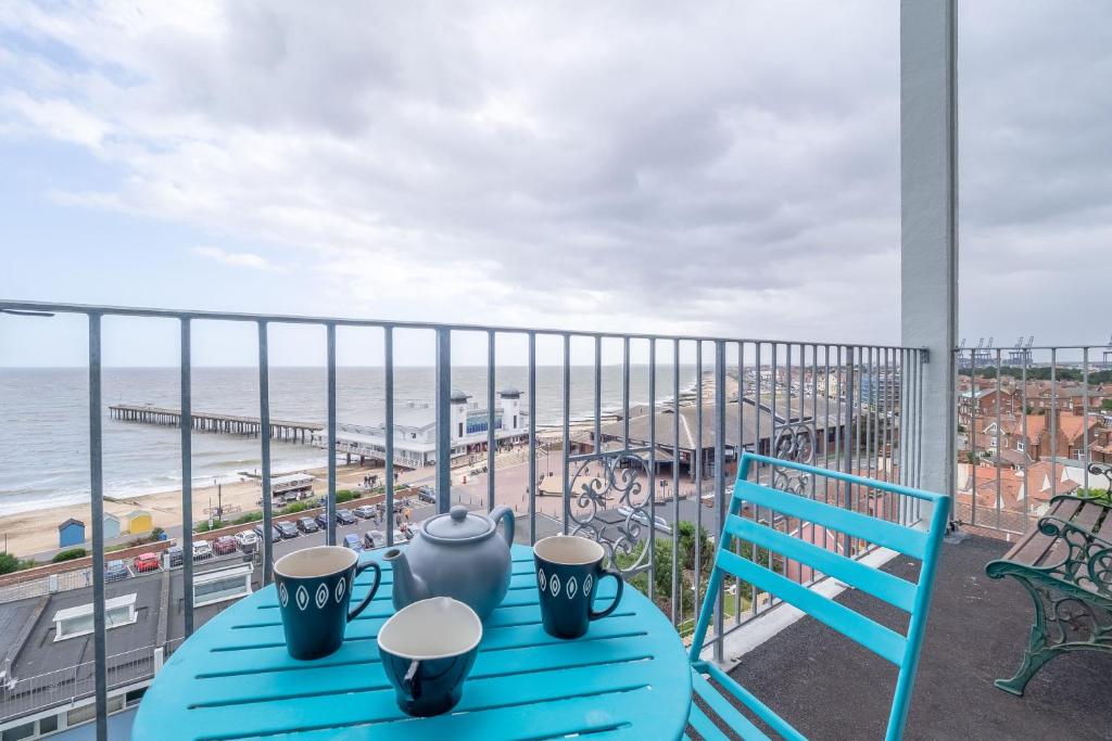 a blue table on a balcony with a view of the beach at 18 Undercliffe in Felixstowe